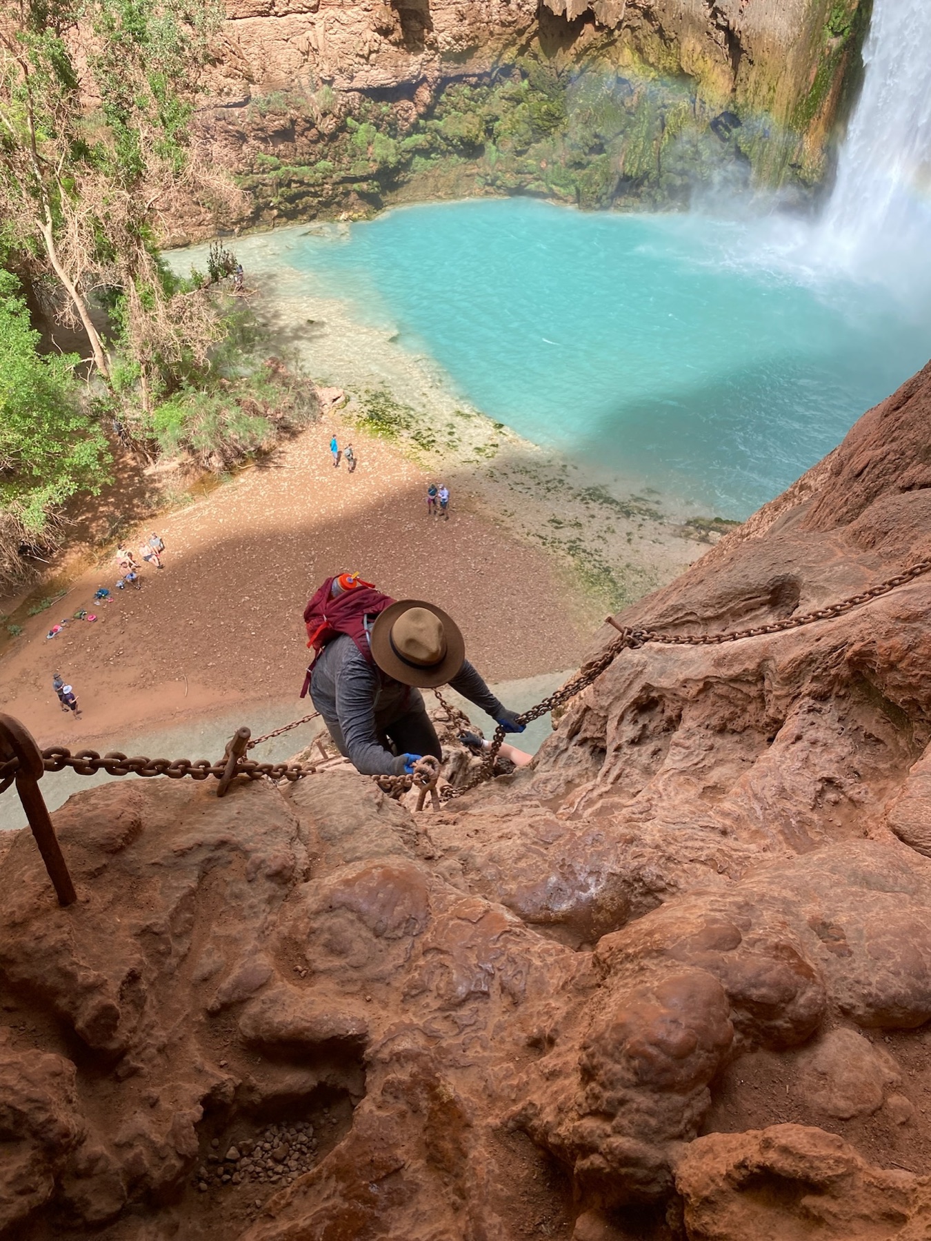 Brandon climbing a chain route above turquoise water at Havasu Falls